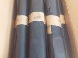 trois rouleaux de tissu noir dans une boîte en carton sur laquelle sont apposées des étiquettes