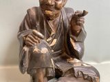 une statue en bronze d'un homme assis sur un rocher