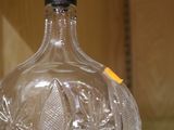une bouteille en verre transparent avec un bouchon noir posée sur une table en verre