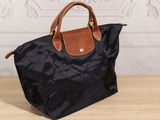 a black and brown bag sitting on top of a wooden table