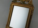 un miroir avec un cadre doré sur lequel est représenté un oiseau
