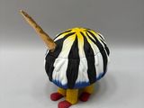 a small figurine of a black and white striped bird with a wooden stick