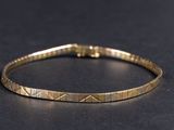 gros plan d'un bracelet en or sur une surface noire