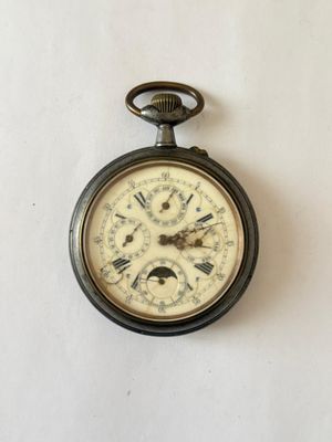 a pocket watch hanging on a wall with roman numerals on it
