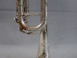 silver plated musical instrument on stand on grey background