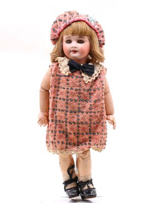 une petite poupée qui porte une robe et un chapeau