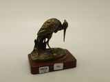 une statue en bronze représentant un oiseau, posée sur un socle en bois