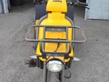 a yellow scooter that is parked in front of a garage