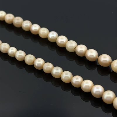 un gros plan sur un collier de perles sur une surface noire