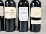 three bottles of red wine are lined up on a table