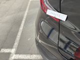 a car parked in a parking lot with a sign attached to the back of it