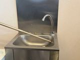 un lavabo en acier inoxydable dans une salle de bains, équipé d'un robinet en métal