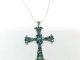 un gros plan d'un pendentif en forme de croix verte sur fond blanc