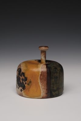 une image représentant un vase marron et noir posé sur une surface blanche