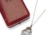 a necklace that has a pearl on it next to a book