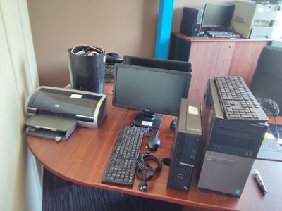 un bureau sur lequel se trouvent un ordinateur, une imprimante et d'autres appareils électroniques