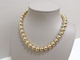 a gold beaded necklace on a mannequin with pearls