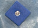 un gros plan d'un diamant dans une boîte bleue posée sur un tissu bleu