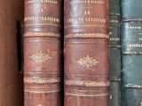 several old books are stacked on top of each other on a shelf