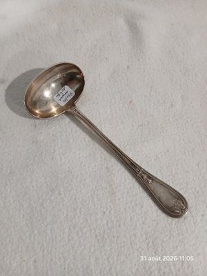 une cuillère plaquée argent posée sur une nappe blanche, sur laquelle est apposée une étiquette