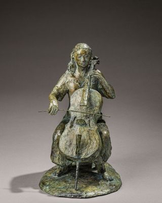 statue en bronze représentant une femme jouant du violoncelle sur un rocher