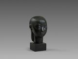 une sculpture noire représentant la tête d'une femme, posée sur un socle noir