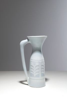 a white pitcher sitting on a table with a gray background