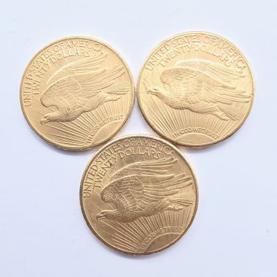 Trois pièces d'or sont représentées sur une surface blanche