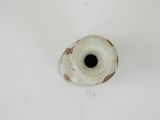 a small white vase with a black hole in it