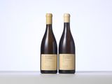 two bottles of wine sitting on top of a table next to each other