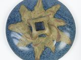 a blue and green plate with a yellow flower on it