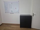 a black cabinet in a room with a white board on the wall