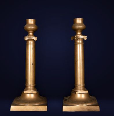 a pair of antique brass candlesticks on marble bases