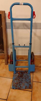 a blue hand truck that is sitting on a tiled floor
