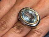 la main d'une femme tenant une bague sertie d'une pierre bleue