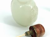 a white vase with a wooden handle next to a white vase