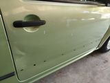 a green car with a black door handle on the side of the road