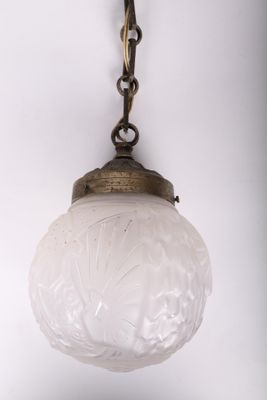 an antique brass and frosted glass hanging light fixture on a chain
