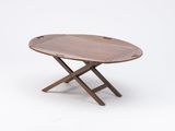 an oval wooden tray with two crossed legs on a white background