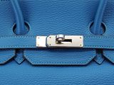 a close up of a blue leather handbag on a white background