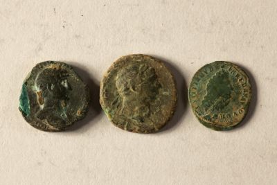 Trois pièces de monnaie romaines antiques sont représentées sur un fond blanc.