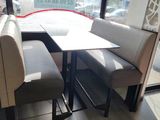 tables and benches in a restaurant with a large window in the background