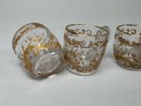 three glass cups with gold designs on them on a white surface