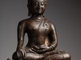 a bronze statue of a seated buddha on a lotus flower