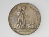 an old silver medal with a woman and a dog on it