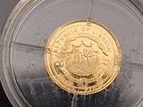 a gold coin in a plastic container on a black surface