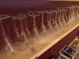 many empty wine glasses lined up on a shelf