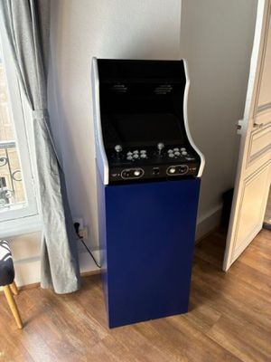 une borne d'arcade bleue et noire dans un coin de la pièce