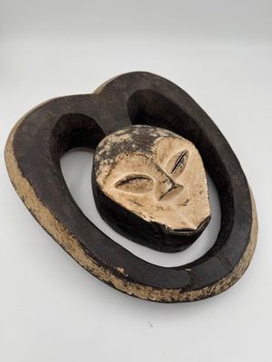 une image représentant une sculpture en bois représentant un visage sur une surface blanche