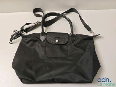 Le sac Longchamp est noir et possède une poignée en cuir.